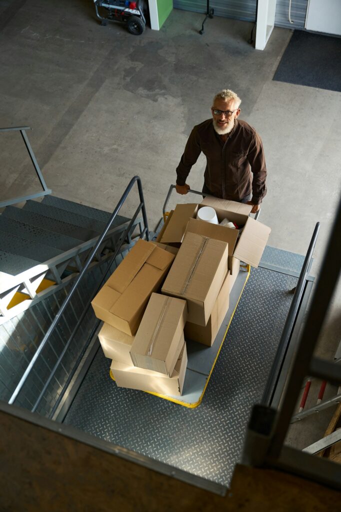 Man lifts a cart with things on a freight elevator